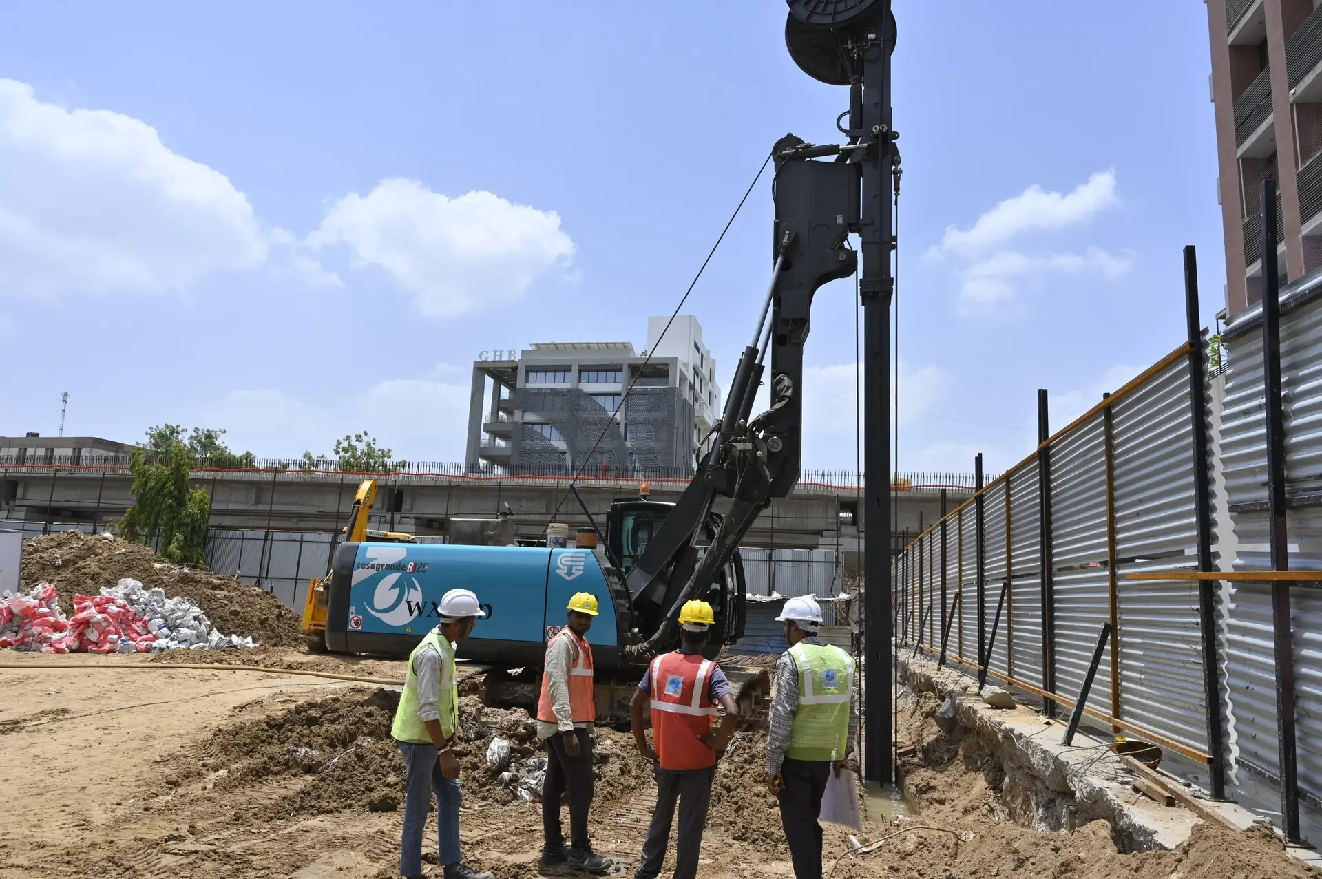 Construction workers inspecting equipment at a diaphragm wall construction site in Jaipur on a clear day.